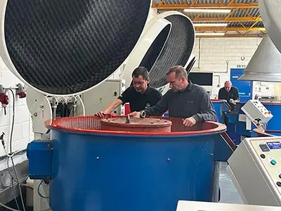 PDJ Vibro - Deburring & Polishing Experts Members of staff standing by a machine